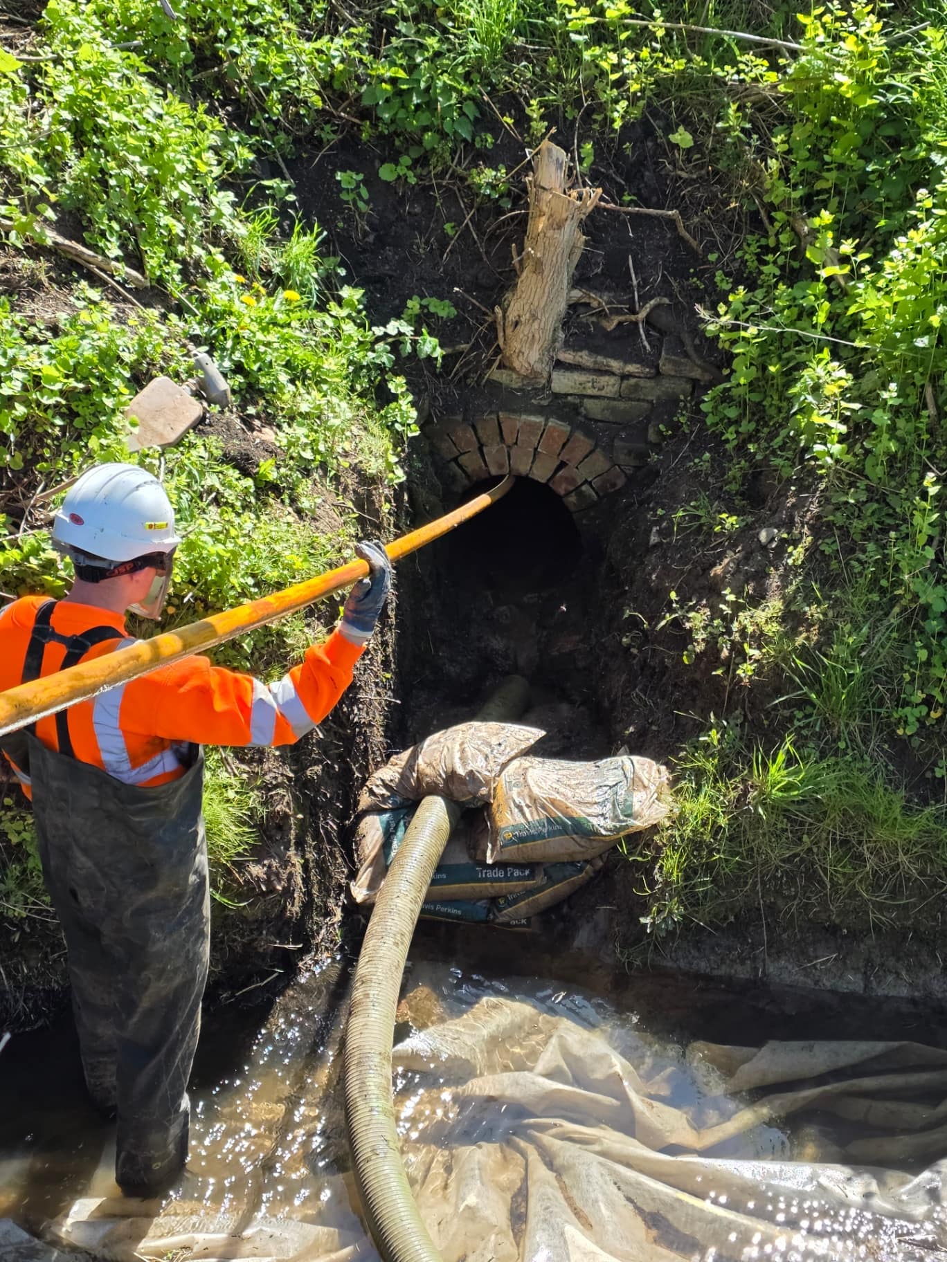 Active Reactive Solutions engineer in waders clearing a culverted watercourse outlet